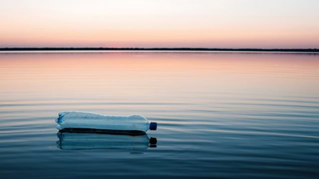 Concept of pollution, creative background. A plastic bottle floating in the ocean, non-decomposable plastic, pollution of the environment. Copy space.