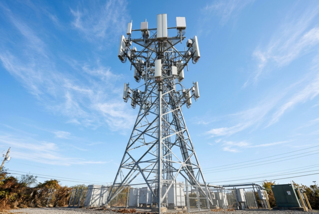 5G tower against blue sky A 5G telecommunications tower with panel antennas against a clear blue sky