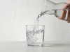 How Much Water Should You Drink a Day? A clear glass of water mid-pour with crisp refraction and rising bubbles