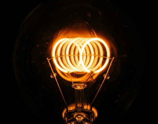 How Does Electricity Work? From Electrons to Your Socket Macro photograph of a glowing incandescent filament coil burning bright against darkness