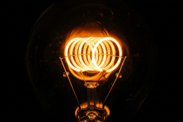 Macro photograph of a glowing incandescent filament coil burning bright against darkness Macro photograph of a glowing incandescent filament coil burning bright against darkness