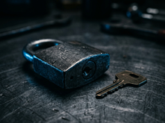 Cybersecurity: Threats, Defences and the Basics A heavy steel padlock and key resting on a dark brushed metal surface in cool light