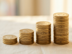 SIP Investing for Beginners: How It Works and Compounds Stacked coins arranged in rising columns on a pale surface in warm side light