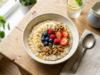 Breakfast: What the Evidence Says and What to Actually Eat Overhead view of a breakfast bowl with oats, banana, berries and nuts on a light table