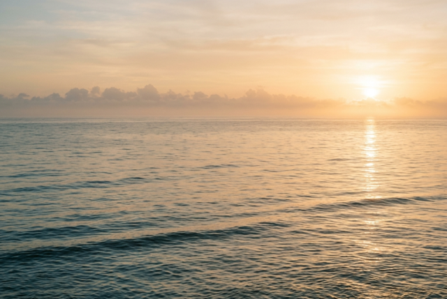 Calm tropical ocean under a hazy warm sky with heat shimmer at the horizon Calm tropical ocean under a hazy warm sky with heat shimmer at the horizon