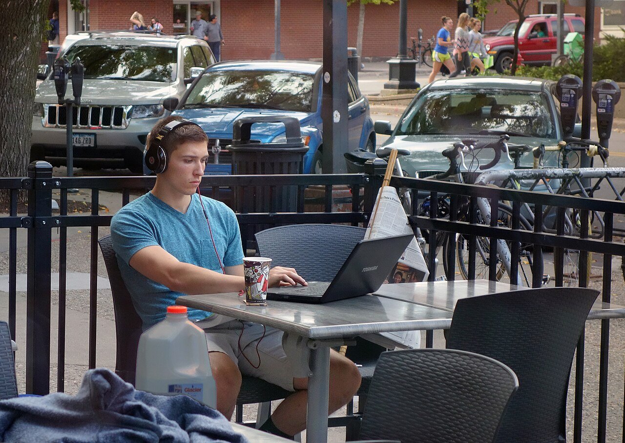 A student in a library working on a laptop with AI study tools