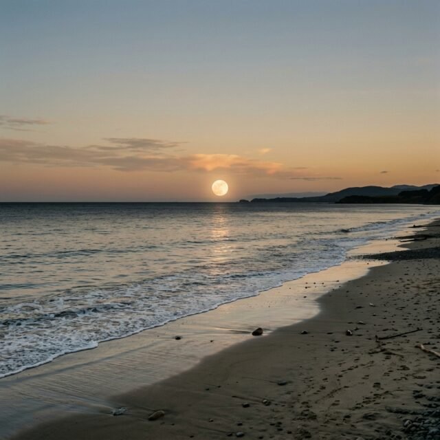 how-tides-work-moon-sun hero Ocean waves rolling onto a beach at low tide with the Moon in the sky