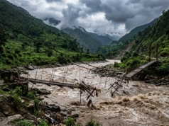 Budhi Gandaki Flood in Gorkha: What We Know (October 2026) AI-generated illustration of a swollen river in a Nepal valley, with a damaged suspension footbridge in floodwater